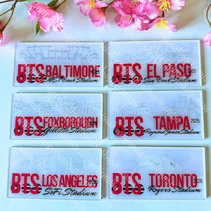 Puede incluir: Posavasos rectangulares de vidrio transparente con texto rojo "BTS" seguido del nombre de una ciudad y un estadio. Los posavasos presentan un dibujo arquitectónico del estadio. Las ciudades incluyen Baltimore, El Paso, Foxborough, Tampa, Los Ángeles y Toronto.