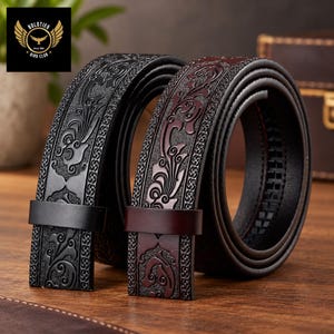 Può includere: Due cinture in pelle arrotolate l'una accanto all'altra, una in nero tinta unita e l'altra in marrone scuro. Entrambe le cinture presentano un intricato motivo floreale in rilievo al centro e un bordo testurizzato, fissate da un passante in pelle.