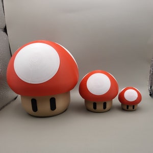 May include: Three red and white mushroom-shaped figurines. The largest mushroom is about 5 inches tall and the smallest is about 2 inches tall.