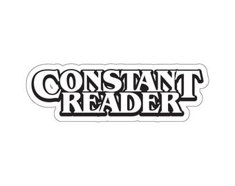 May include: Black and white sticker with the text "CONSTANT READER" in a bold, stylized font.
