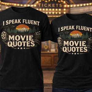 May include: Two black t-shirts with the text "I SPEAK FLUENT MOVIE QUOTES" in a vintage design. The design includes a mountain scene with a sunset, trees, film reel, and stars. The shirts are displayed in front of a theater.