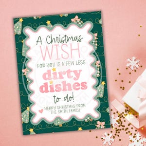 May include: A Christmas greeting card with a green background and a white scalloped border. The card reads "A Christmas Wish for you is a few less dirty dishes to do!" in a playful font. The card is decorated with Christmas trees and bows.