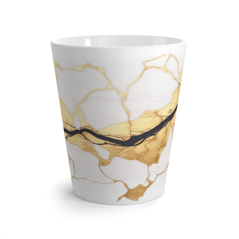 May include: White ceramic mug with a gold and black marbled design. The mug has a wide base and a tapered top.