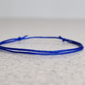 May include: A simple blue cord bracelet with a knotted closure.