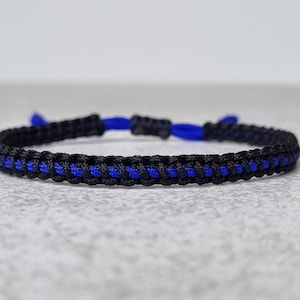 Op de afbeelding: Een gevlochten armband in zwart en blauw met een schuifknoop sluiting.