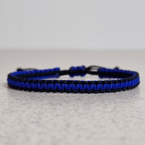 May include: A blue and black braided friendship bracelet with a knotted closure.