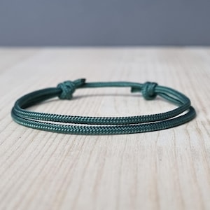 Op de afbeelding: Een donkergroene gevlochten touw armband met een eenvoudige knoop sluiting.