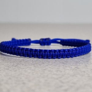 May include: A blue braided friendship bracelet with a knotted closure.