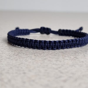 Könnte beinhalten: Ein geflochtenes Armband in Marineblau aus Kordel.
