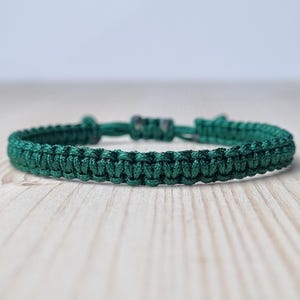 May include: A dark green braided bracelet with a silver clasp.