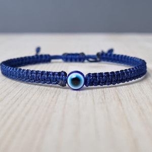 May include: A dark blue braided bracelet with a blue and white evil eye charm.