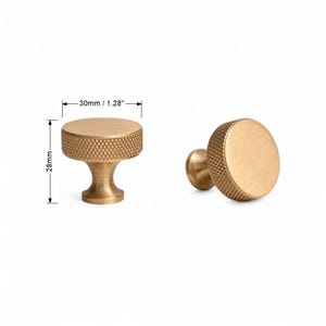 Detailed view of solid brass gold knobs – minimalist furniture hardware on white background.