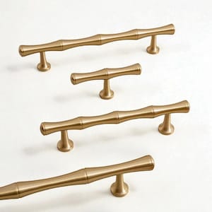 May include: A collection of gold-colored bamboo-style cabinet pulls. The pulls have a cylindrical shape with a textured surface, and are mounted on small, round bases. The hardware is arranged on a white background.