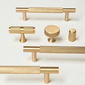 Solid brass gold handles and knobs – modern minimalist cabinet hardware set on white background.