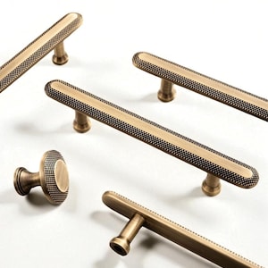 以下が含まれることがあります： アンティーク真鍮製のキャビネット金具の詰め合わせ。長いバープルがいくつか、ノブが1つあります。プルは、点線模様の縁取りがある長方形で、丸みを帯びた短いポストに取り付けられています。ノブにも同様の点線模様があります。