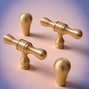 Brushed gold solid brass knobs and handles displayed on gradient background – modern minimalist cabinet hardware.