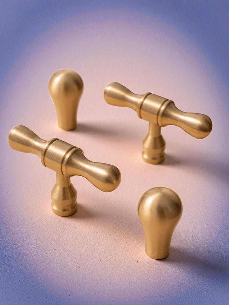 Brushed gold solid brass knobs and handles displayed on gradient background – modern minimalist cabinet hardware.