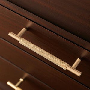 Solid brass gold handles installed on wooden drawers – modern minimalist cabinet pulls.