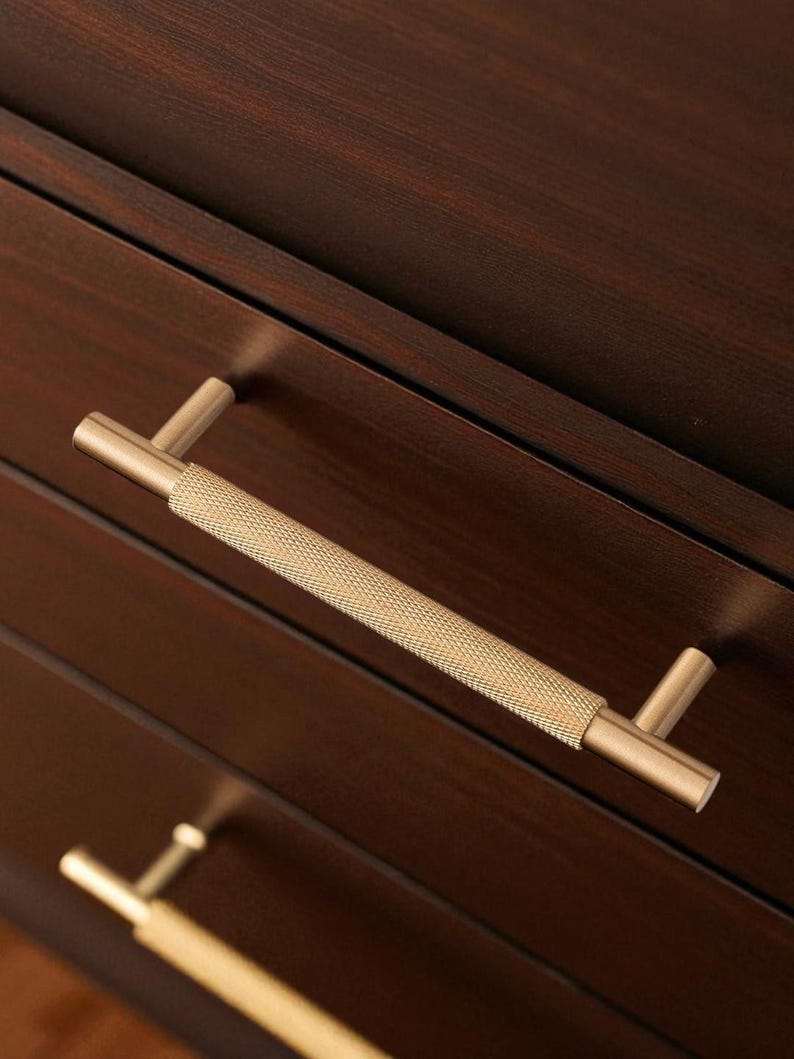 Solid brass gold handles installed on wooden drawers – modern minimalist cabinet pulls.