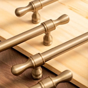 Brushed gold solid brass handles installed on wooden drawers – modern minimalist furniture pulls.