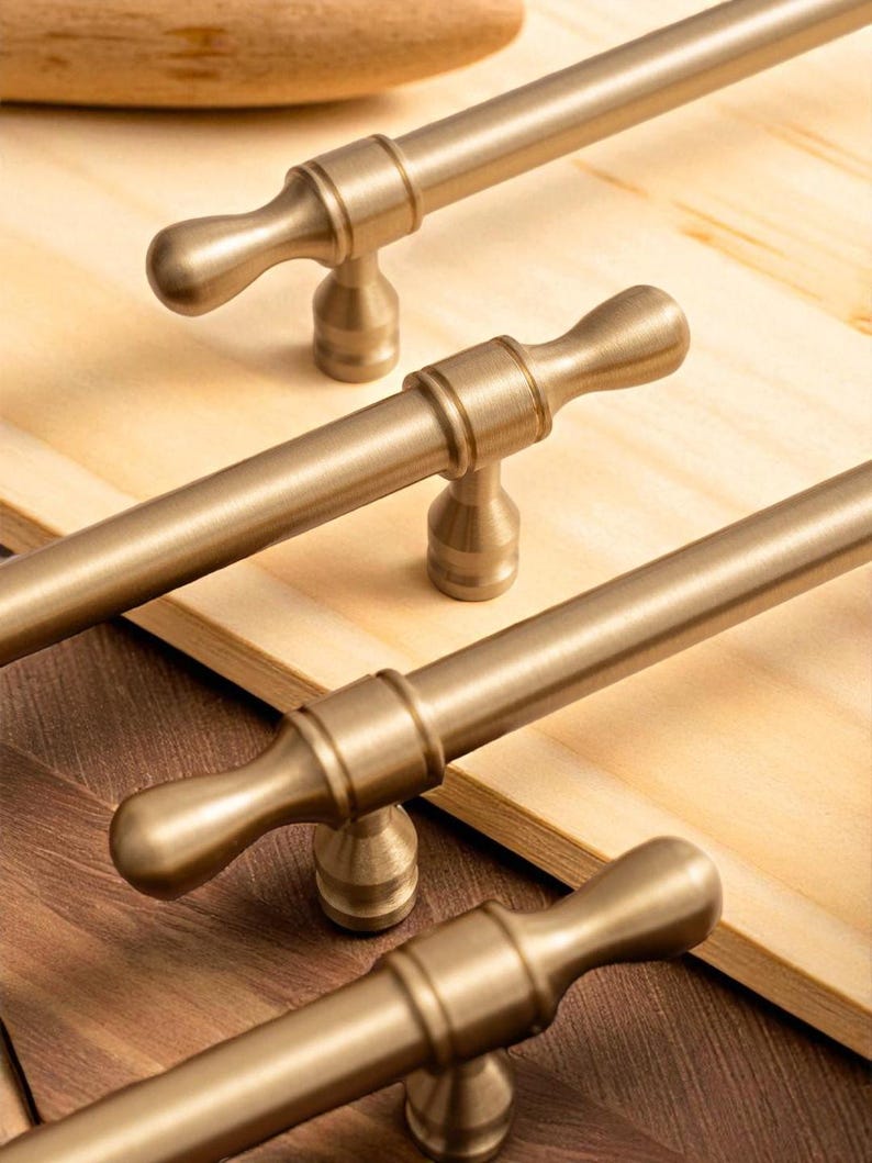 Brushed gold solid brass handles installed on wooden drawers – modern minimalist furniture pulls.