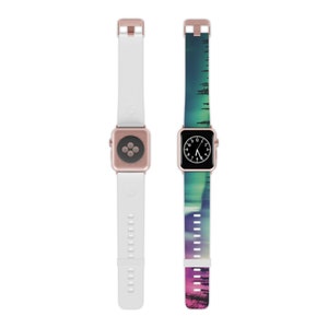 May include: Two Apple Watch bands, one white and one with a colorful aurora borealis design. The aurora band has a pink, purple, green, and blue gradient with a silhouette of trees at the bottom.