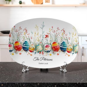 May include: Oval ceramic Easter platter with colorful Easter eggs and floral design. The platter has the text "The Petersons" and "Easter 2026". The platter is supported by a silver metal stand.