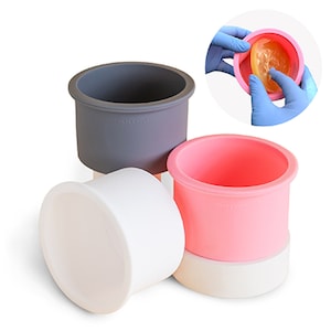 May include: Three silicone cake molds, one gray, one pink, and one white. The molds are stacked on top of each other. The pink mold is being used to show how the mold can be used to make a cake.