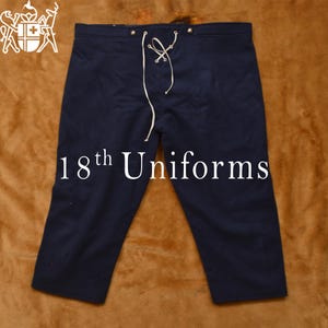 May include: Dark blue knee-length pants with a white drawstring and metal buttons. The pants are made of a thick, woven fabric. The text "18th Uniforms" is printed on the front of the pants.