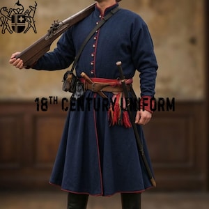 May include: A dark blue 18th century uniform coat with red piping, silver-toned buttons, and a high collar. The garment is worn with a brown leather belt, a multi-colored sash with red tassels, a shoulder strap, and a long-barreled musket.