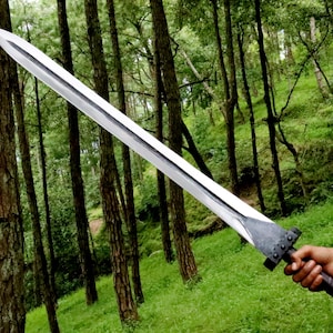 May include: A long, silver sword with a wide blade and a dark handle. The sword is held against a backdrop of a lush green forest. The blade appears to be approximately 30 inches long.