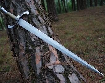 Könnte beinhalten: Ein Stahlschwert mit zweischneidiger Klinge, silberfarbenem Parierstange mit geschwungenen Parierstangen und einem strukturierten, hellen Griff. Die Waffe verfügt über einen metallischen Knauf und eine spitz zulaufende Klinge mit polierter Oberfläche.