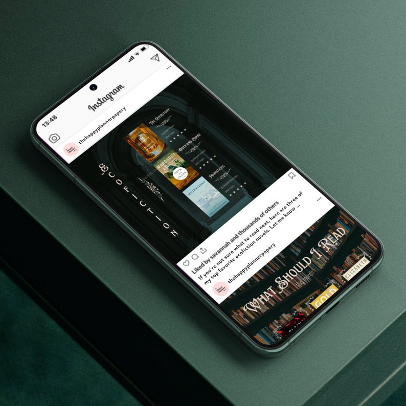 K&ouml;nnte beinhalten: Ein Smartphone-Bildschirm zeigt einen Instagram-Post von thehappyplannerpapery. Der Beitrag zeigt eine Liste von drei &Ouml;ko-Fiction-Romanen mit dem Text "What Should I Read?" und ein B&uuml;cherregal im Hintergrund.