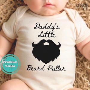 May include: White baby onesie with black text that reads "Daddy's Little Beard Puller" and a black silhouette of a beard.