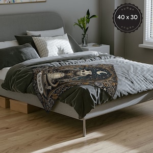 May include: A black and gold throw blanket featuring a whimsical illustration of an opossum with a crescent moon and stars. The blanket includes the text "The Opossum" in a vintage font.