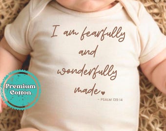 May include: A white baby onesie with the text "I am fearfully and wonderfully made - PSALM 139:14" in brown lettering. The onesie is made of premium cotton.