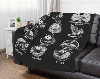 May include: Black and white throw blanket with a design of opossums representing each zodiac sign. The signs are Aries, Taurus, Gemini, Cancer, Leo, Virgo, Libra, Scorpio, Sagittarius, Capricorn, Aquarius, and Pisces.