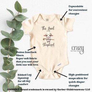 May include: A beige baby onesie with a graphic of a lamb holding a shepherd's staff. The text "The Lord is my Shepherd" is printed on the onesie. The onesie has expandable shoulders for easy changes, ribbed leg openings for comfort, and high-positioned snaps for quick diaper changes.