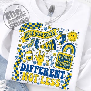 May include: White sweatshirt with a colorful graphic design. The design includes the text "ROCK YOUR SOCKS", "DIFFERENT NOT LESS", and "CHOOSE INCLUSION". The design also features socks, hearts, a coffee cup, a sun, and a rainbow.