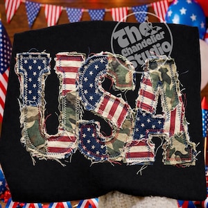 May include: Black sweatshirt with the word "USA" appliqued in a patchwork design. The letters feature the American flag and camouflage patterns, with a distressed, frayed edge. The Chandelier Studio logo is visible.