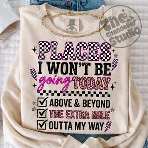 May include: Cream-colored sweatshirt with the text "PLACES I WON'T BE going TODAY" in black, pink, and leopard print. The design includes lightning bolts, stars, and checkmarks with phrases like "ABOVE & BEYOND". A gold chain necklace is draped on top.