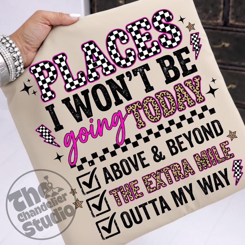 May include: Beige throw pillow with the text "PLACES I WON'T BE GOING TODAY" in black, pink, and leopard print. Additional text includes "ABOVE & BEYOND", "THE EXTRA MILE", and "OUTTA MY WAY". Decorative stars and lightning bolts.