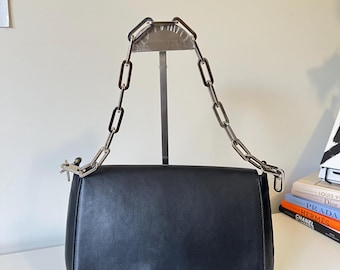 Auténtico bolso de hombro pequeño de piel negra GUCCI con correa plateada, limpio y en buen estado. De segunda mano.