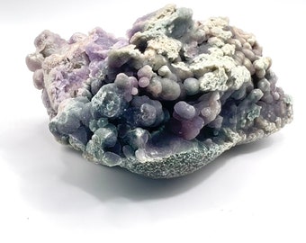 May include: A large, purple and white agate geode with a rough, textured surface. The geode is filled with small, round, purple and white agate nodules.