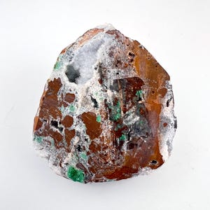 Puede incluir: Una geoda &aacute;spera, marr&oacute;n y blanca con una cavidad llena de cristales blancos e inclusiones verdes.