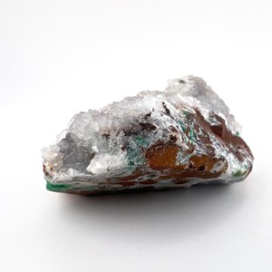 Puede incluir: Un c&uacute;mulo de cristales blanco, verde y marr&oacute;n con una textura rugosa y natural.