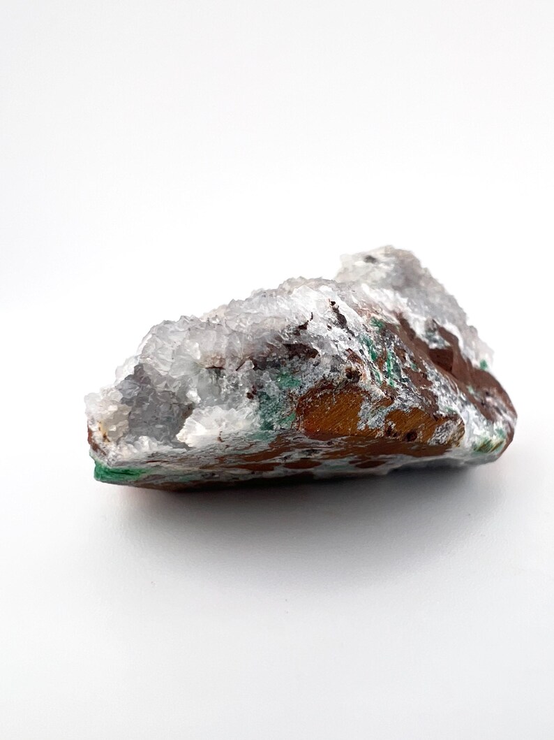 Puede incluir: Un c&uacute;mulo de cristales blanco, verde y marr&oacute;n con una textura rugosa y natural.