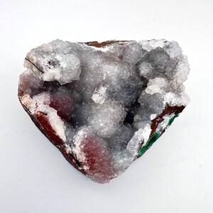 Puede incluir: Una geoda en forma de coraz&oacute;n con un interior blanco y cristalino. El exterior es una mezcla de marr&oacute;n, rojo y verde.