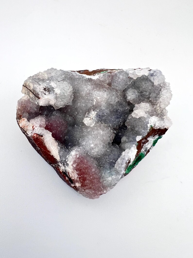 Puede incluir: Una geoda en forma de coraz&oacute;n con un interior blanco y cristalino. El exterior es una mezcla de marr&oacute;n, rojo y verde.