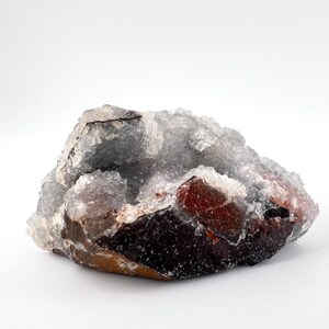 Puede incluir: Un c&uacute;mulo de cristales blancos transl&uacute;cidos con una base marr&oacute;n rojiza. Los cristales tienen una textura rugosa y natural.
